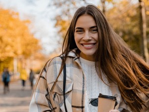 smiling young woman with fall trees in the background