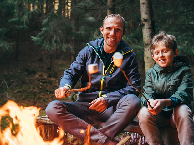 Happy father and son roasting marshmallows over a campfire