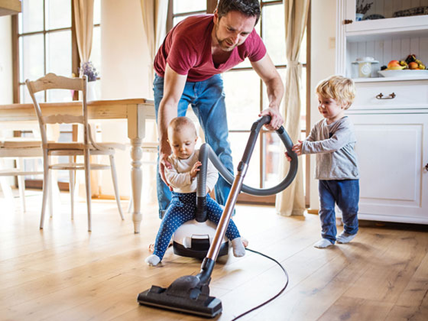 Dad and two young kids vacuuming