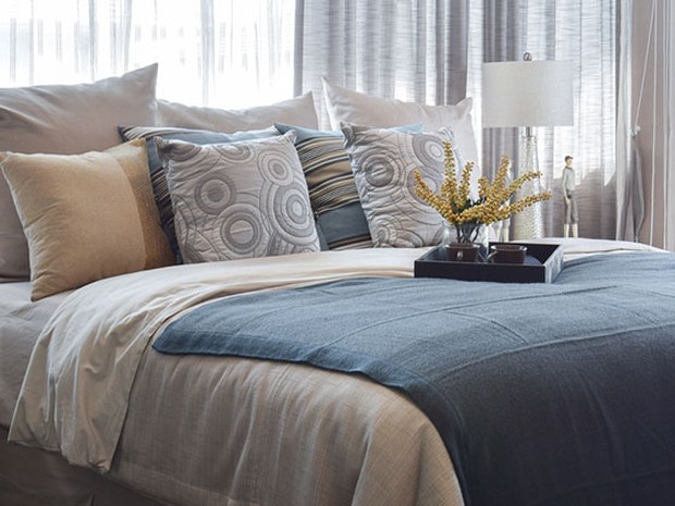 Bed with blue comforter and patterned throw pillows